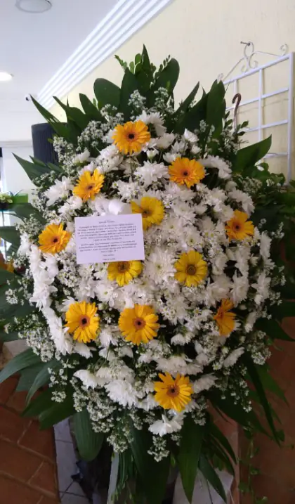 Coroa Gota com Gérbera — coroa de flores em Salvador. Coroa em formato de gota, com gérberas amarelas e crisântemos brancos.